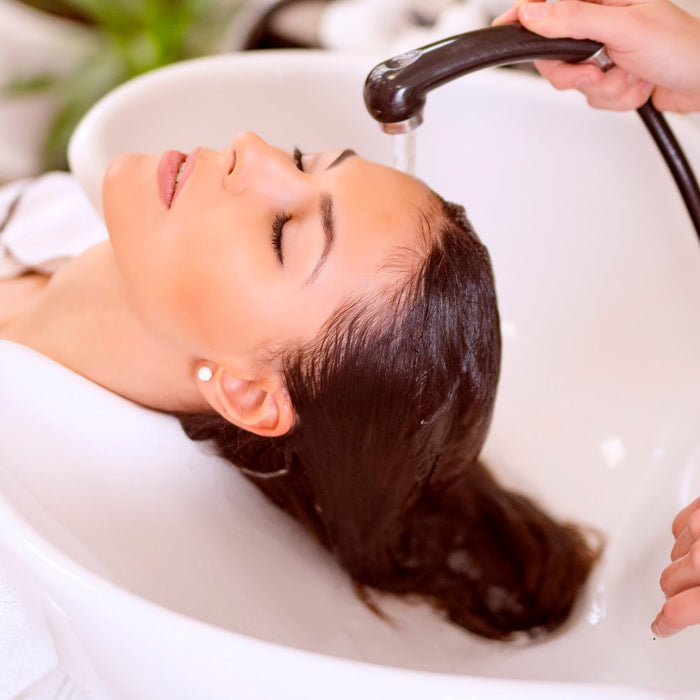 White shampoo wash bowl. Women getting hair washed at a salon in a white sink